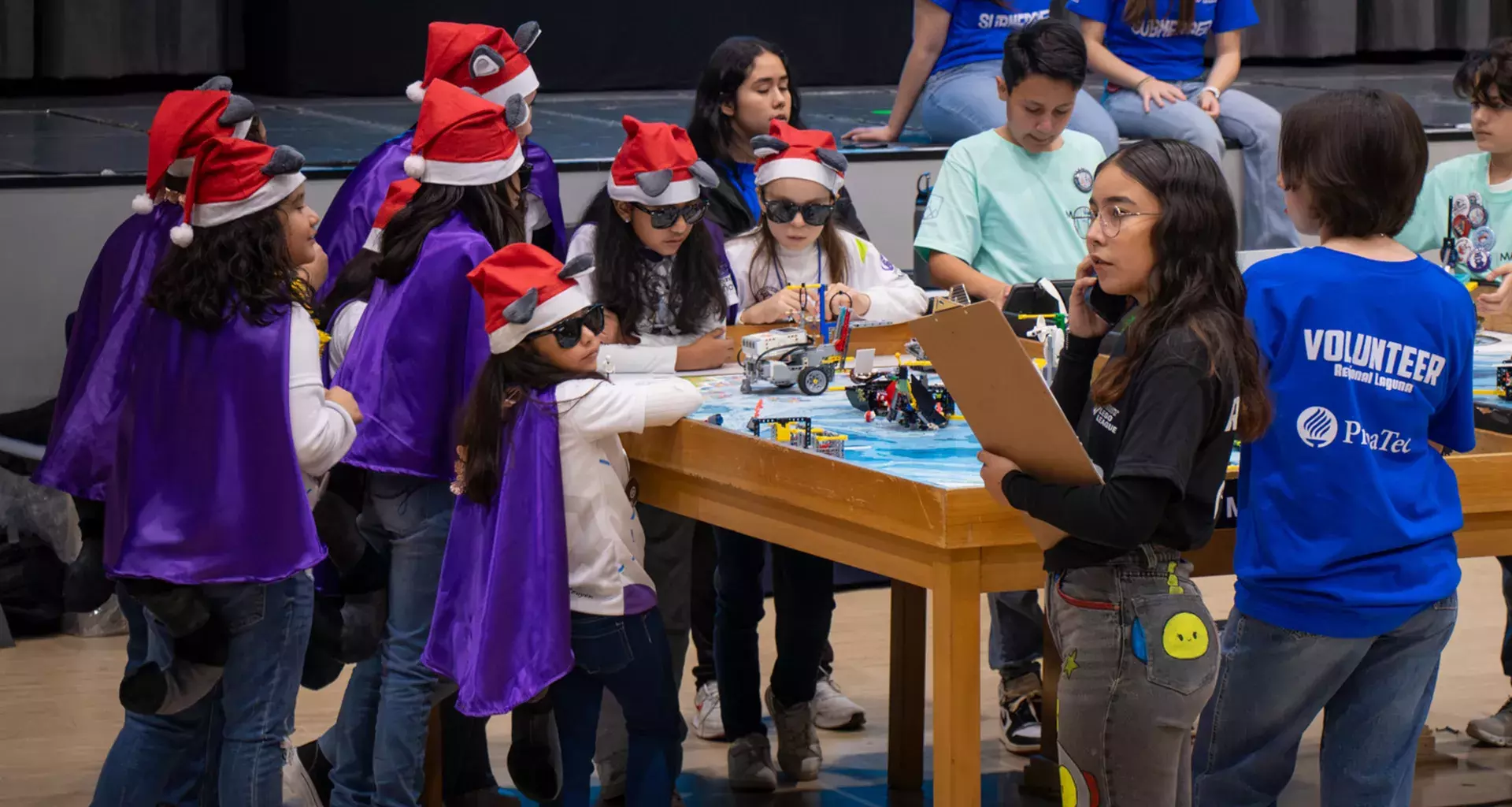 Niñas con gorro navideño y lentes participan en el juego del robot de FIRST LEGO League en PrepaTec Laguna