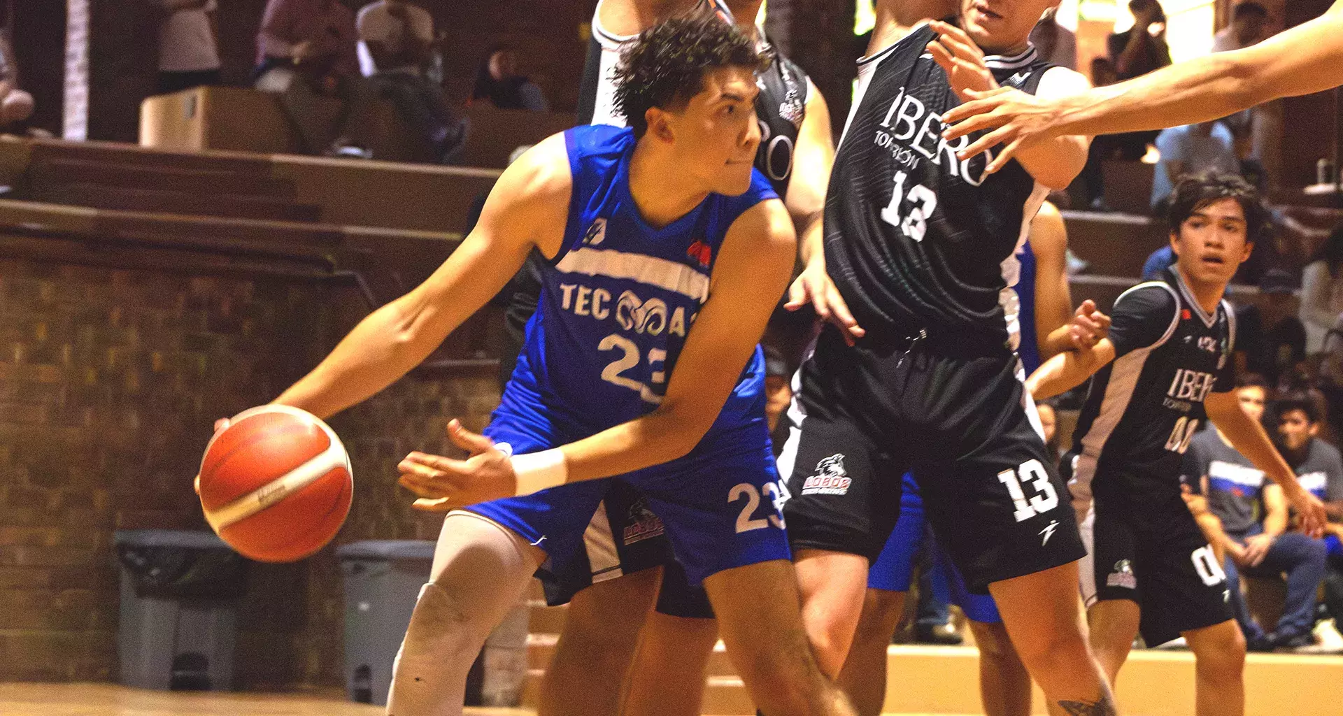 Jugador de básquetbol con uniforme de Borregos Laguna disputa el juego contra atletas con uniforme negro