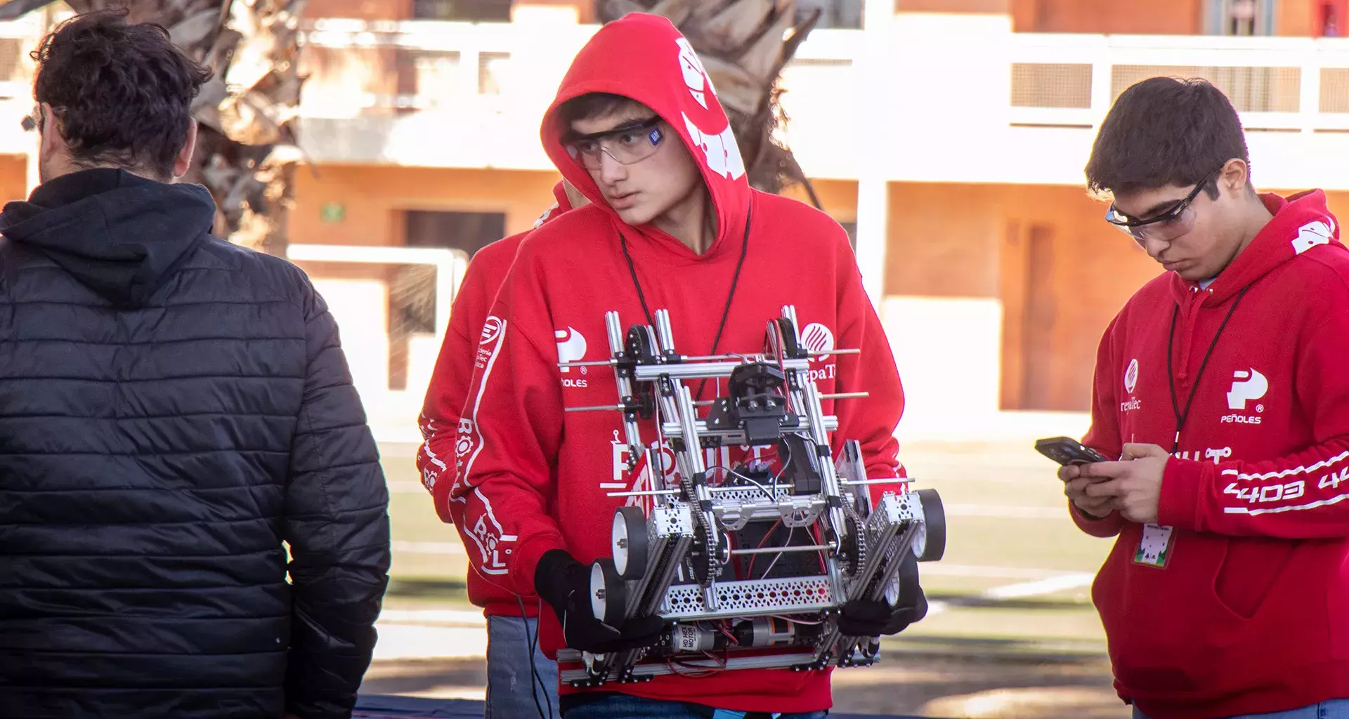 Estudiante joven lleva robot en sus manos en su participación en competencia de robótica