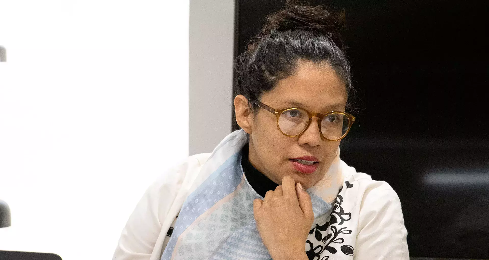 Profesora con lentes, ropa blanca y el cabello sujetado