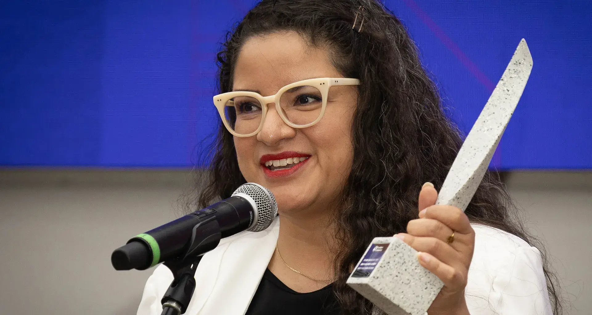 Mujer hablando y en la mano sostiene estatuilla del Premio Mujer Tec 2025.