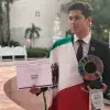 Paco Zamora, foto de ganador, con su premio, reconocimiento y bandera de México.