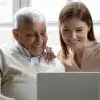 Adulto mayor y mujer joven usando una laptop