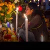 Mujer frente a ofrenda del Día de Muertos