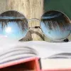 libro abierto y sobre éste, unos lentes de sol que reflejan palmeras