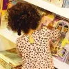 Una niña de cabello chino observa los libros en un stand de la Feria Internacional del Libro de Monterrey 2023. 