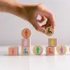 Mano acomoda bloques de madera con iconos que representan la diversidad de personas en la sociedad.