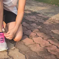 Persona agachada abrochando las agujetas de sus tenis