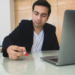 Jóven escribiendo en una mesa de vidrio