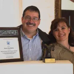 Profesor deteniendo reconocimiento junto a su esposa