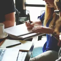 Jóvenes estudiantes en mesa de trabajo.