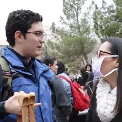 Alumno sosteniendo muletas y maestra con cubre bocas. 