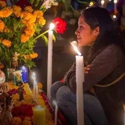 Mujer frente a ofrenda del Día de Muertos