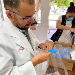 doctor abre paquete de proyecto nabawa de egresados del Tec con caretas médicas para combatir covid19.