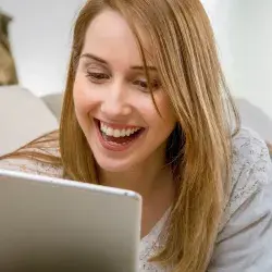 mujer mirando su tablet mientras sonríe