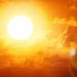 Fotografía del sol reflejando sus rayos en el cielo con tonalidades rojizas/naranjas por altas temperaturas.