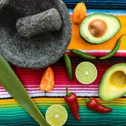 Imagen de manta con molcajete, aguacate, limón y chiles.