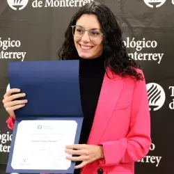 La profesora Jeanette Conesa posando junto a su reconocimiento.