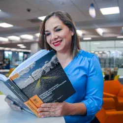 Adriana Morales leyendo un libro en el que participó como coautora