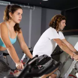 Gente en gimnasio en bicicletas estáticas