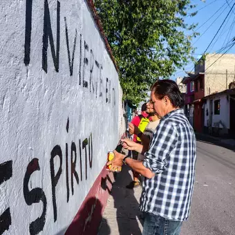 Alumnos y Armando Alanís pintando paredes con frases poéticas