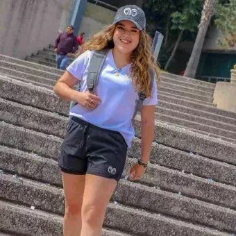 Chica modelando shorts y gorra gris con logo borregos