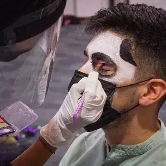 Un alumno está siendo maquillado por su comunidad