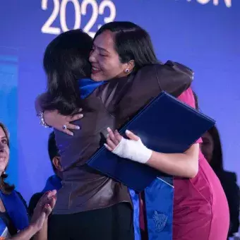 Maestra y graduada abrazándose