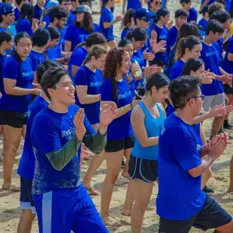 alumnos bailando en grupo en la orilla de la playa