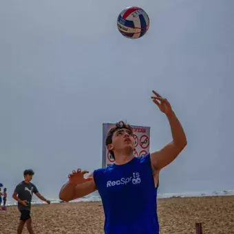 Alumno jugando voleibol en la playa