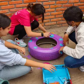 Alumnos decorando llantas para el patio del colegio en Voluntariado Tec