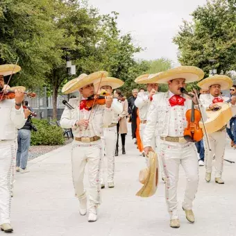 Mariachi va tocando una canción mientras caminan detrás de él los asis