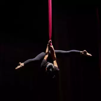 Chica de cabeza colgada de telas en número de danza aérea. 