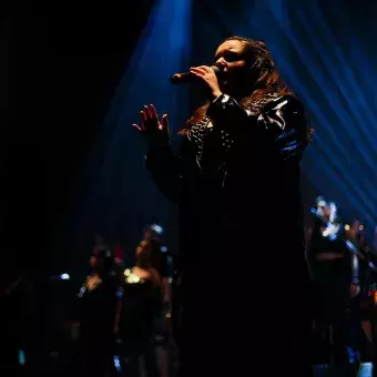 Cantante vestida de negro con luz iluminando su cara. 