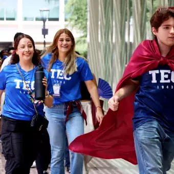 Alumnos corriendo por el campus con capas de color guindo.