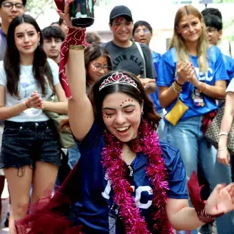 Alumna baila mientras alumnas y alumnos celebran.