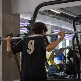 Estudiante utilizando el equipo de pesas