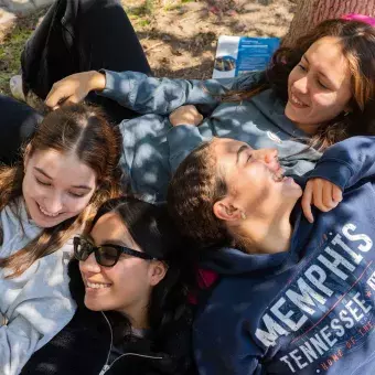 Alumnas acostadas en jardín sonriendo