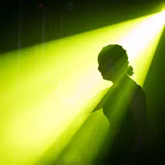 Nallely Ponce, actriz y bailarina, iluminada por un haz de luz verde en el escenario de Tec's Got Talent, creando una silueta.