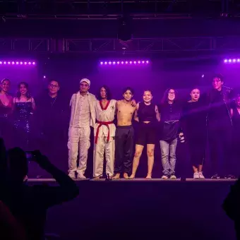 Estudiantes de las comunidades de profesional REVO y KREI que participaron en Tec's Got Talent, posando bajo luces moradas.