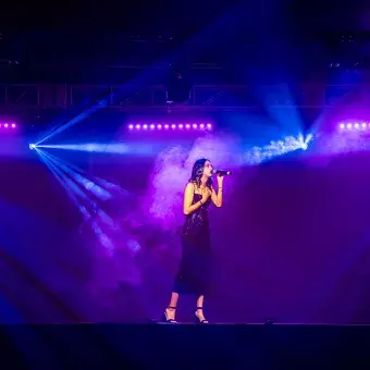 Valentina, estudiante de Estudios Creativos y cantante, interpretando en el escenario de Tec's Got Talent. Vestida de negro, rodeada de luces azules y púrpuras.