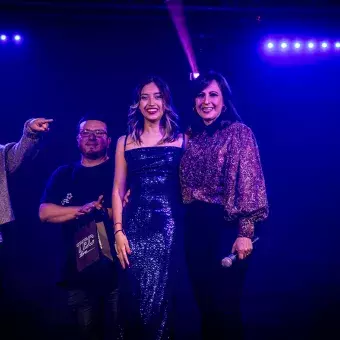 Valentina, ganadora del primer lugar en Tec's Got Talent, posando junto a la mentora de la comunidad REVO y los jueces, rodeada de luces azules.