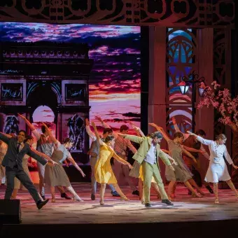 bailarinas y protagonistas de la obra bailando en el escenario, parís está de fondo 