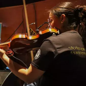 Chica parte de la compañía de música, se encuentra tocando el violín 