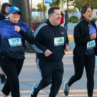 Tres personas corriendo y cruzando la meta