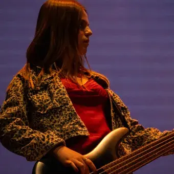 Mujer bajista en escenario.