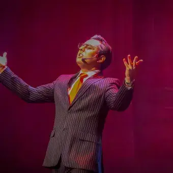 Estudiante con los brazos abiertos cantando en musical Legalmente Rubia.