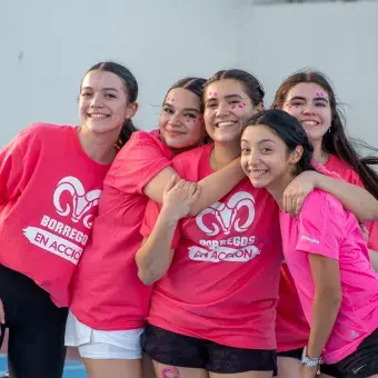 Grupo de alumnas de preparatoria vestidas de rosa posando juntas. 