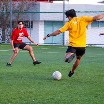 Jóvenes universitarios jugando fútbol.