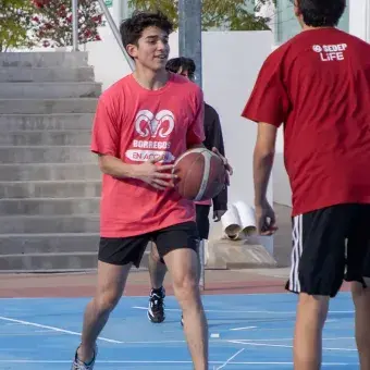 Jóvenes de preparatoria jugando básquetbol.